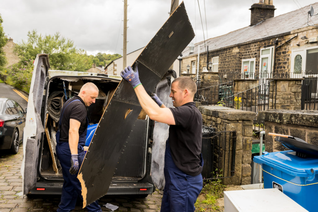 Newtons Waste Removal team loading a van with a black wooden board